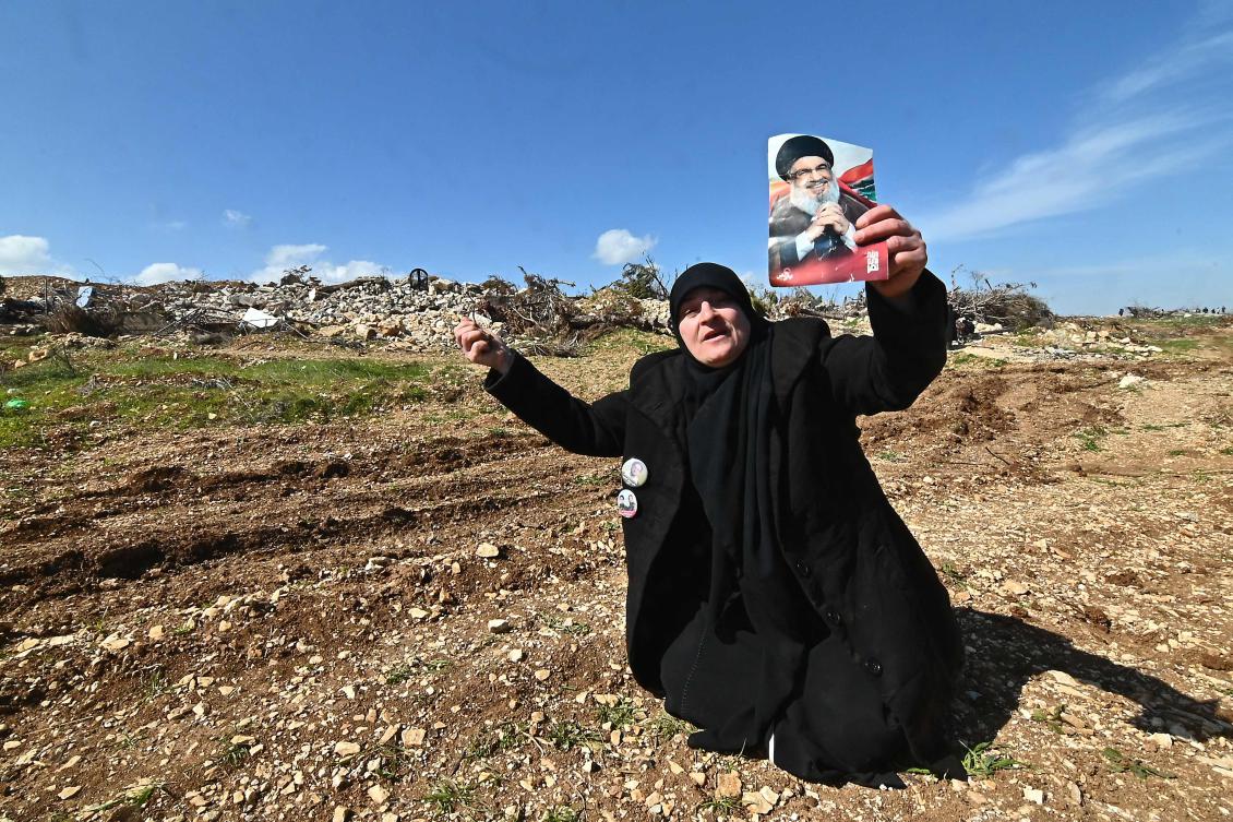 A woman holds a portrait of slain Hezbollah leader Hassan Nasrallah as residents return accompanied by the Lebanese army to the devastated southern Lebanese village of Maroun el Ras, on February 18, 2025. (AFP)