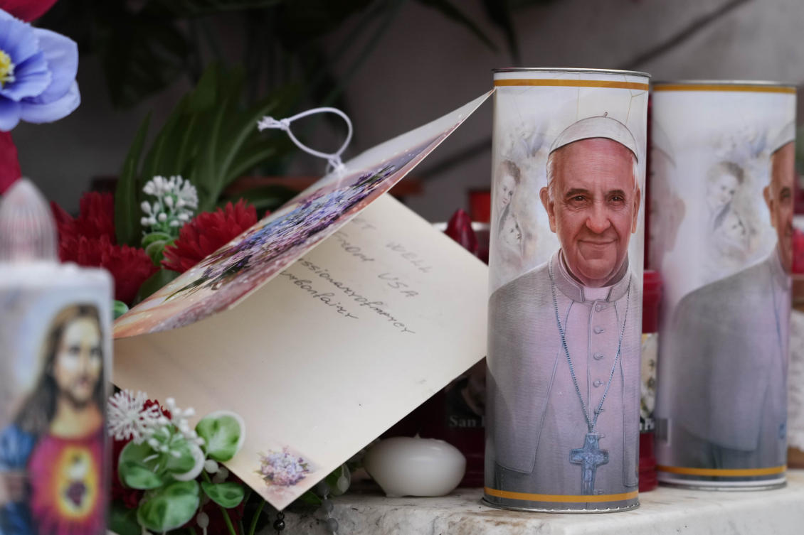 Candles with the pictures of Pope Francis are the laid under the statue of late Pope John Paul II outside Agostino Gemelli Polyclinic in Rome, Feb. 19, 2025, where the Pontiff is hospitalized since Feb. 14. (AP)