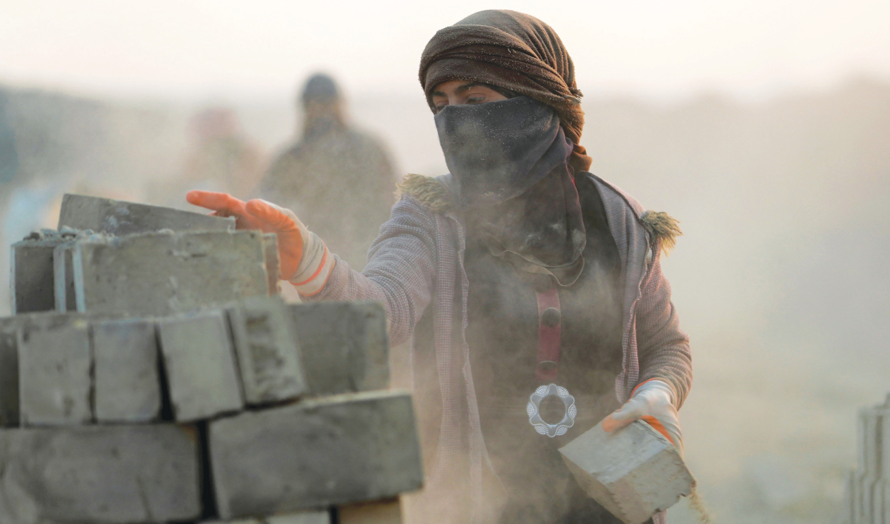 Rukaya Ghali loads clay bricks onto a donkey-pulled cart, at a factory in Al-Kifl district on the outskirts of Hilla in central Iraq. (AFP)