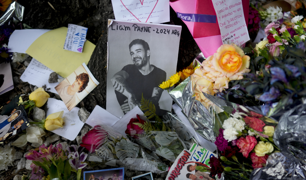 A picture of former One Direction singer Liam Payne is surrounded with flowers and candles as part of a makeshift memorial outside the hotel where he fell from a balcony to his death, in Buenos Aires, Argentina, Oct. 17, 2024. (AP)