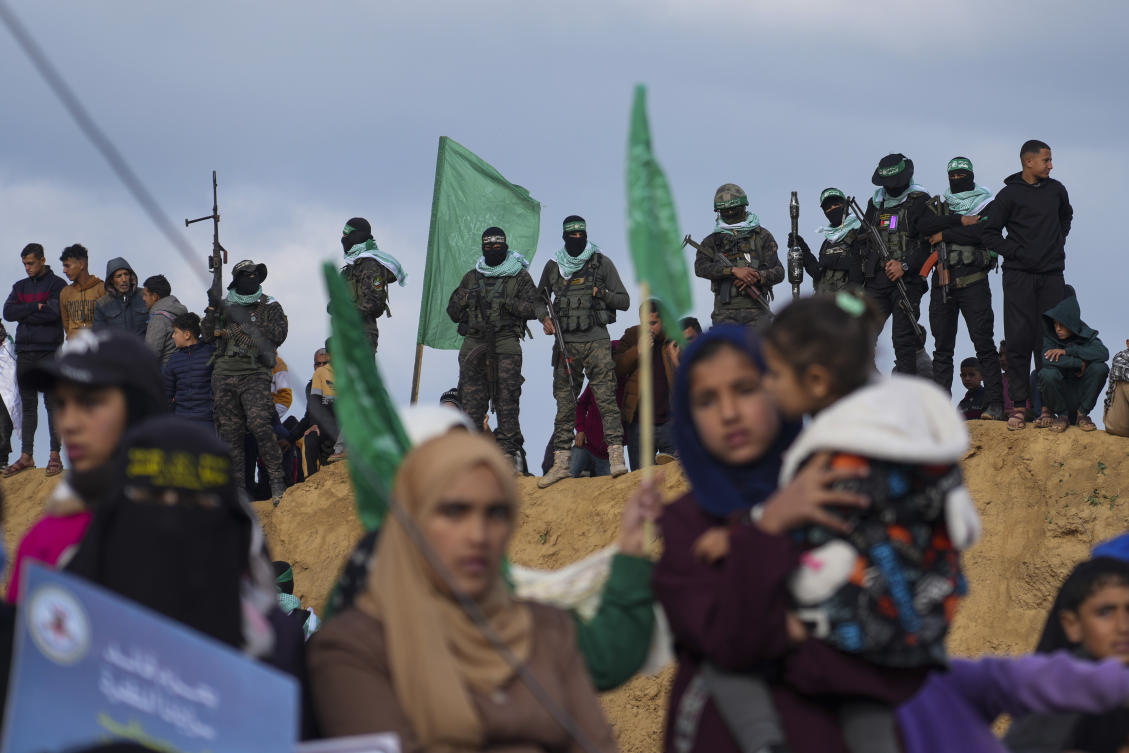 Palestinians watch as Hamas fighters take up a position ahead of handing over four bodies to the Red Cross in Khan Younis, southern Gaza Strip, Feb. 20, 2025. (AP)