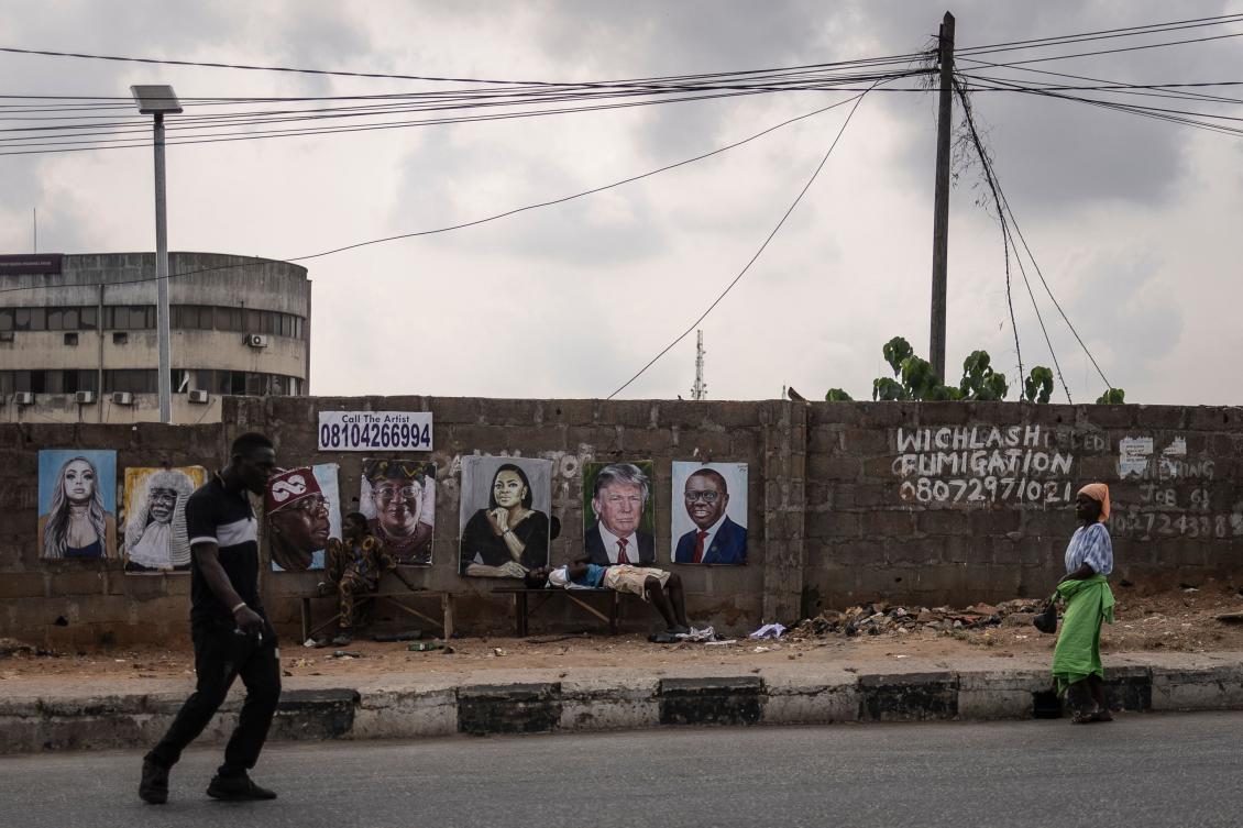 A pedestrian walks next to paintings of the President of Nigeria Bola Tinubu (3rd L on wall) and US President Donald Trump (2nd R on wall) displayed in the street in Lagos, on February 21, 2025. (AFP)