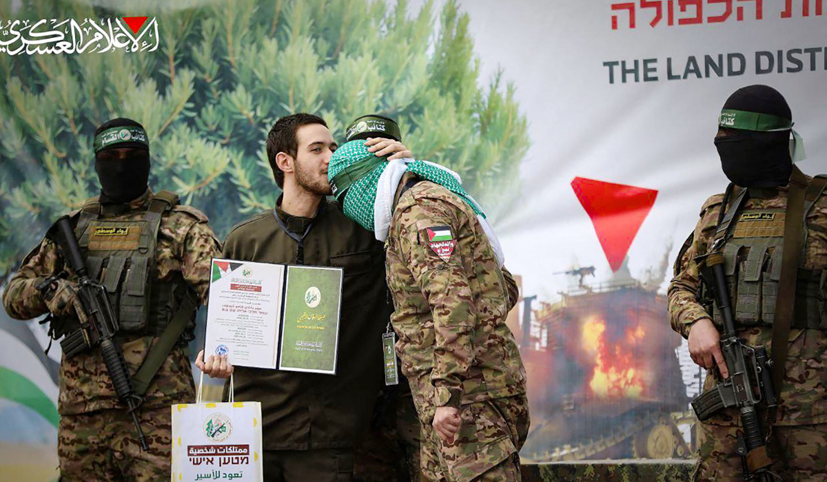 This handout image released by the Hamas Media Office on February 22, 2025, shows newly-released Israeli hostage Omer Shem Tov kissing the head of a Hamas fighter shortly after being set free in Nuseirat in the central Gaza Strip. (AFP)