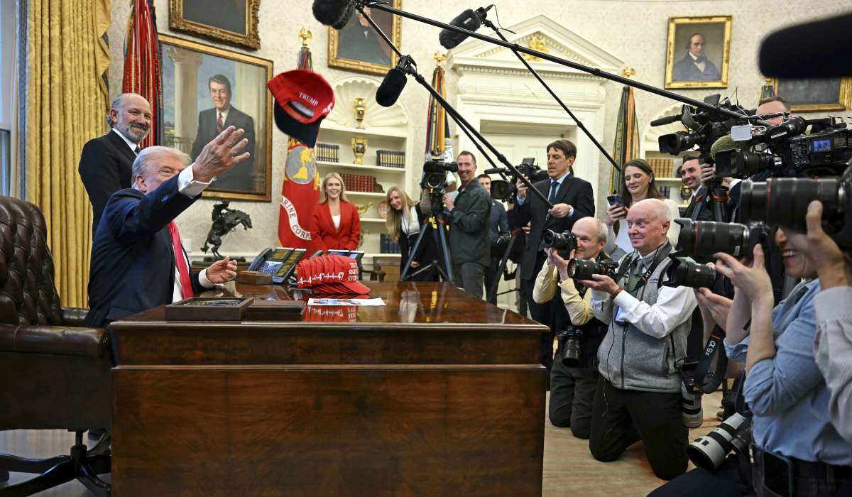 President Donald Trump throws a hat that reads "Trump Was Right About Everything" as he talks to reporters while Commerce Secretary Howard Lutnick, and White House press secretary Karoline Leavitt, back center, watch, in the Oval Office at the White House in Washington, Tuesday, Feb. 25, 2025. (AP)