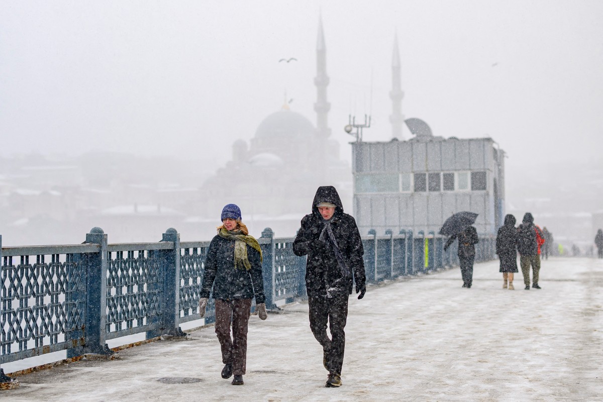 Pedestrians walk on the Galata Bridge as snow falls in Istanbul on February 21, 2025 (AFP)