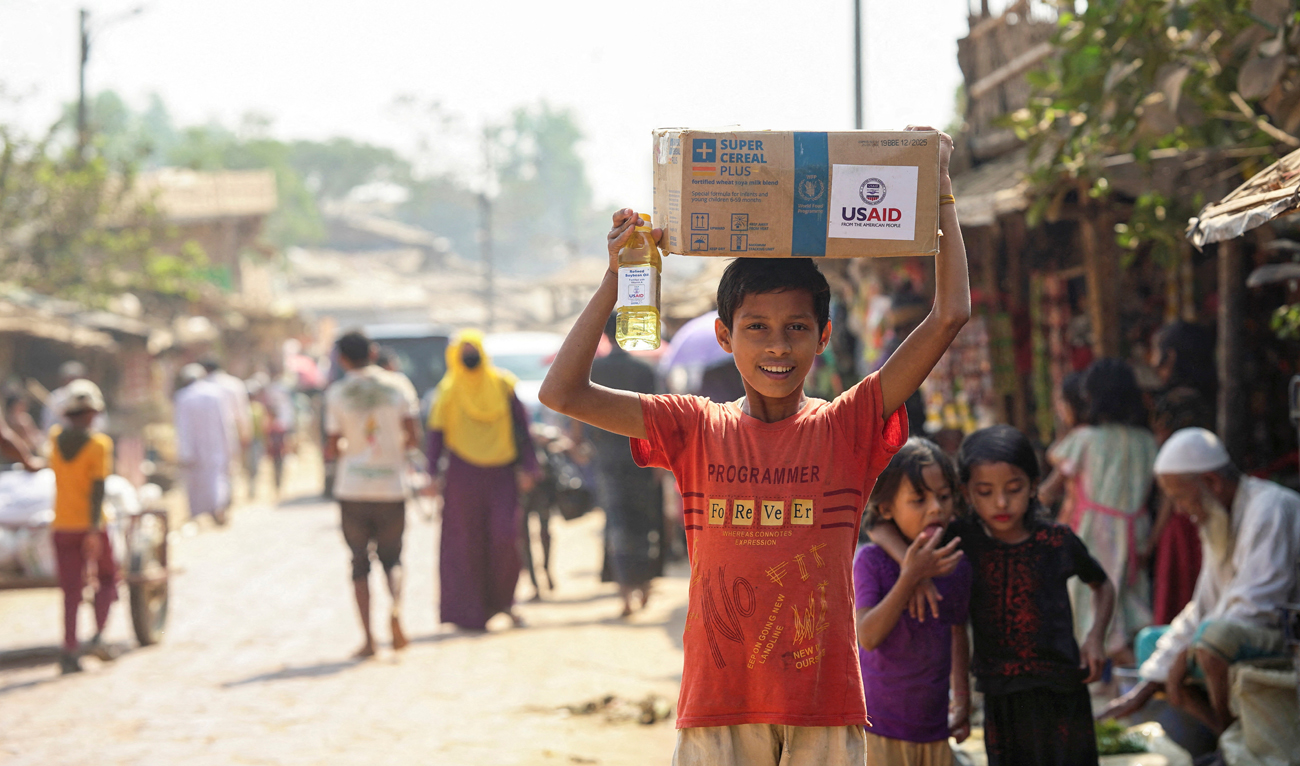 A Rohingya boy reacts as he carries a relief supply package with the USAID logo on it, at a refugee camp in Cox’s Bazar, Bangladesh on February 11, 2025. (REUTERS)