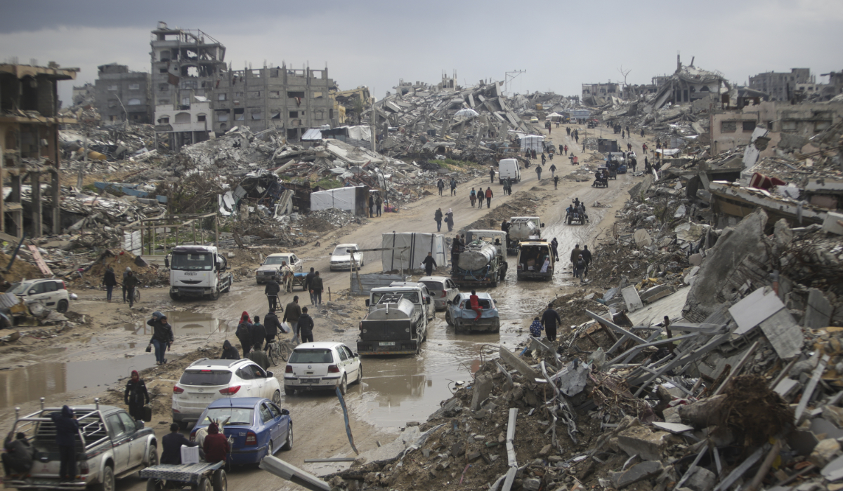 Cars and pedestrians move along a road amid widespread destruction caused by the Israeli military in Gaza. (AP)