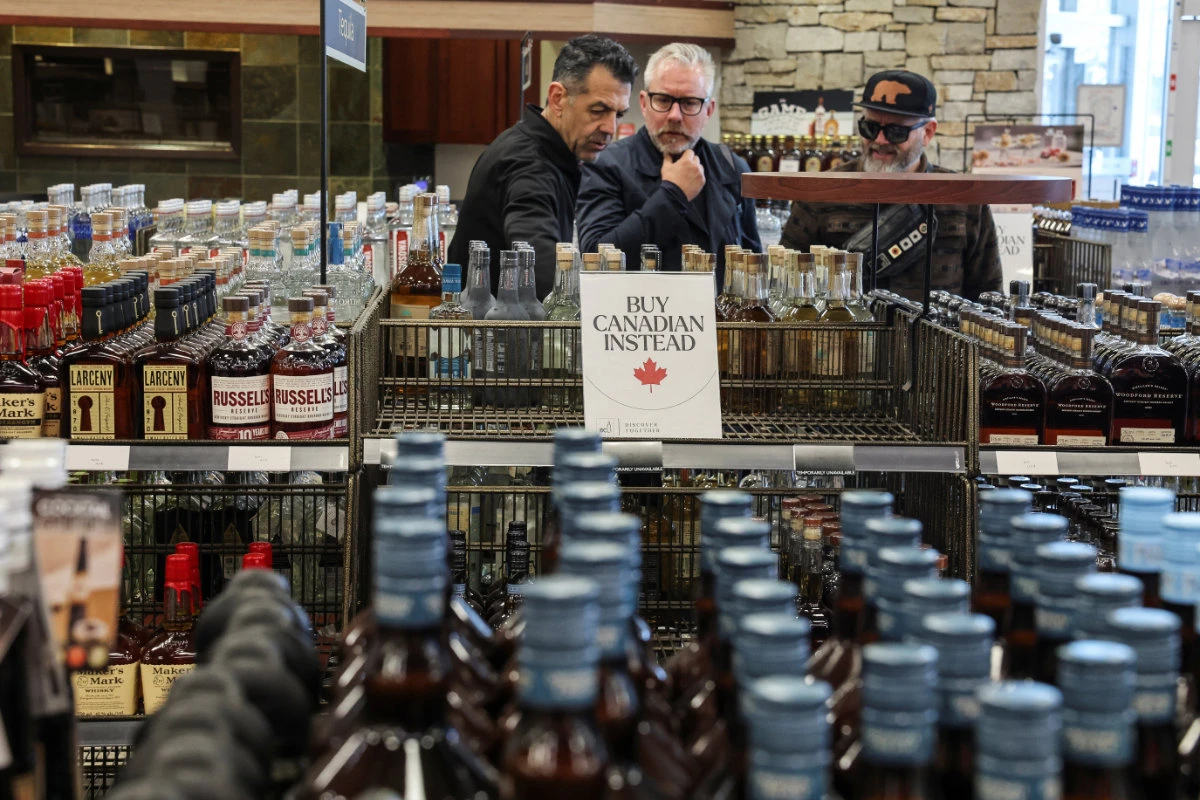 People look on as empty shelves remain with signs "Buy Canadian Instead" after the top five US liquor brands were removed from sale at a B.C. Liquor Store in Vancouver, on February 2, 2025, as part of a response to US President Donald Trump's 25% tariffs on Canadian goods. (Reuters)