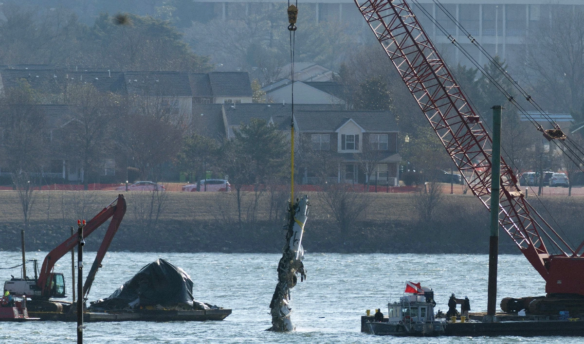 A crane pulls up a portion of the damaged plane during recovery efforts after the American Airlines crash on February 04, 2025 in Arlington, Virginia. (AFP)