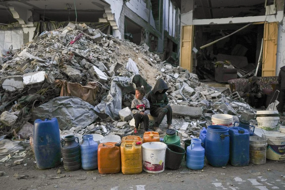 Two children wait to get water next to a line of empty jerrycans in an area largely destroyed by the Israeli army’s air and ground offensive in Gaza City, Feb. 5, 2025. (AP)
