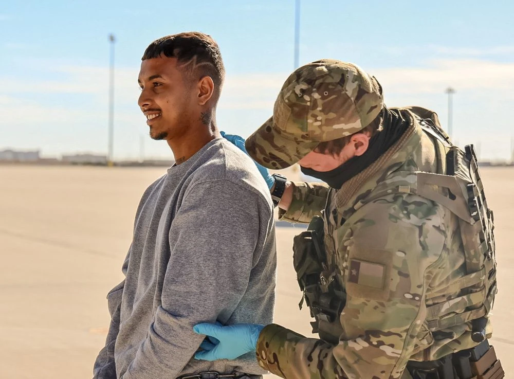 A federal agent checks a detained migrant, one of several, who a US government spokesperson referred to as ‘highly dangerous criminal aliens,’ before boarding a flight to Guantanamo, Feb. 4, 2025. (Reuters)