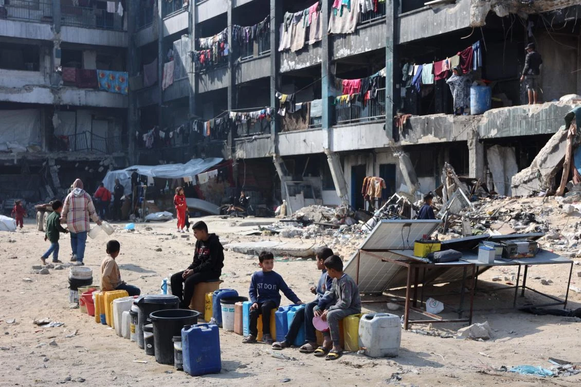Palestinian children sit and wait next to water cans at a school turned shelter in Jabalia in the northern Gaza Strip on Feb. 4, 2025. (AFP)
