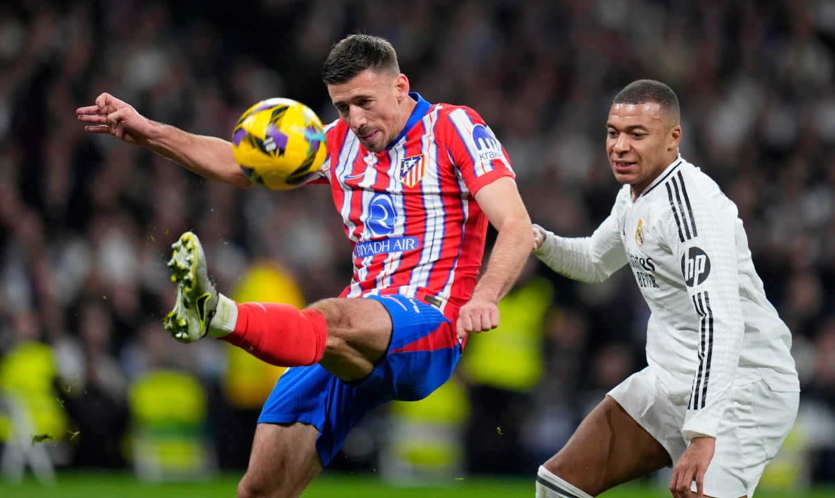 Atletico Madrid's Clement Lenglet clears the ball away from Real Madrid's Kylian Mbappe, right, during a Spanish La Liga soccer match between Real Madrid and Atletico Madrid at the Santiago Bernabeu stadium in Madrid, Saturday, Feb. 8, 2025. (AP)