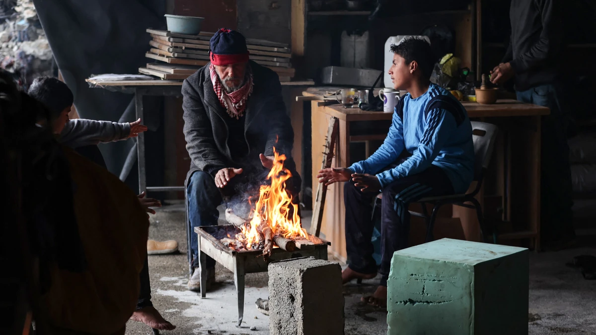 Palestinians warm themselves around a fire inside a makeshift shelter in Beit Hanun in the northern Gaza Strip, Feb. 12, 2025. (AFP)