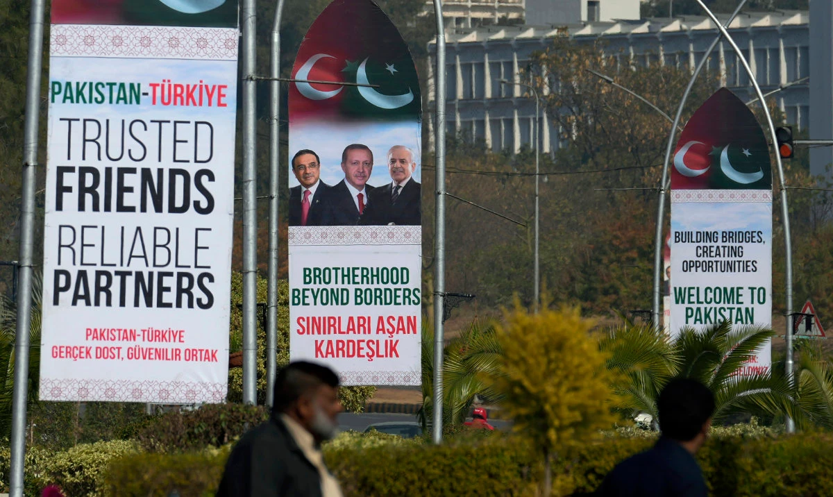 People walk past welcoming billboards with the pictures of Turkish President Recep Tayyip Erdogan, Pakistan's President Asif Ali Zardari and Prime Minister Shehbaz Sharif display on a road in Islamabad, Pakistan, Wednesday, Feb. 12, 2025. (AP)