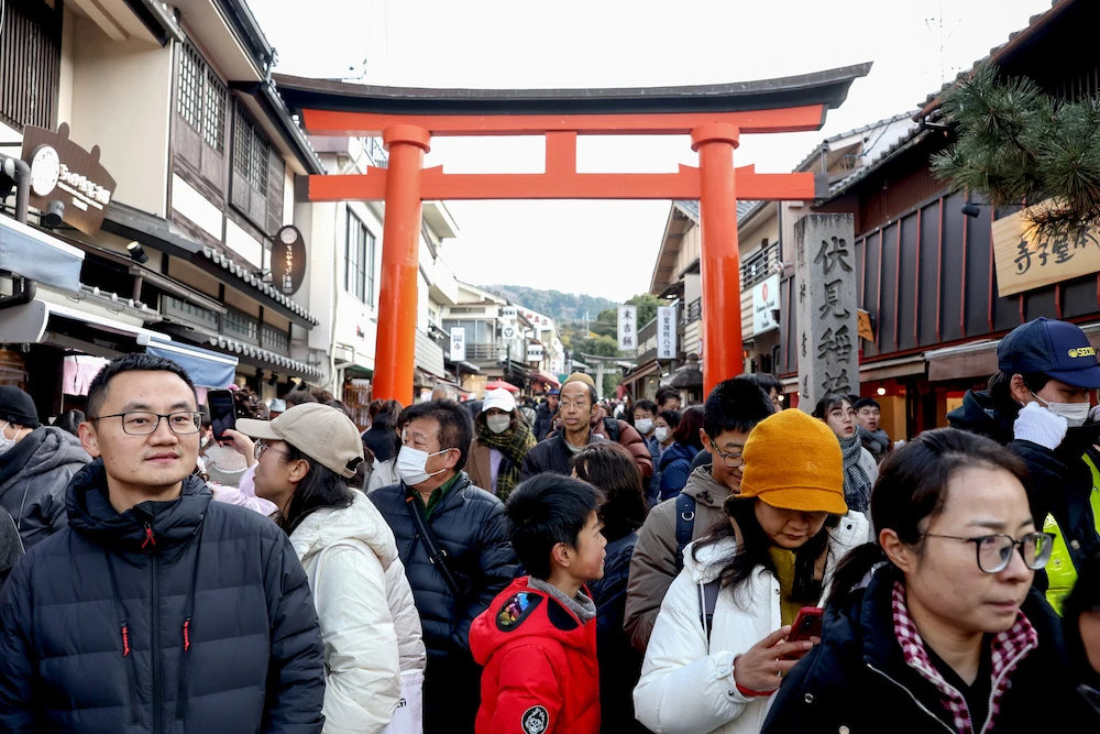 Tourists walk past shops during a visit to Fushimi Inari Shrine in the city of Kyoto on Jan. 13, 2025. (AFP)