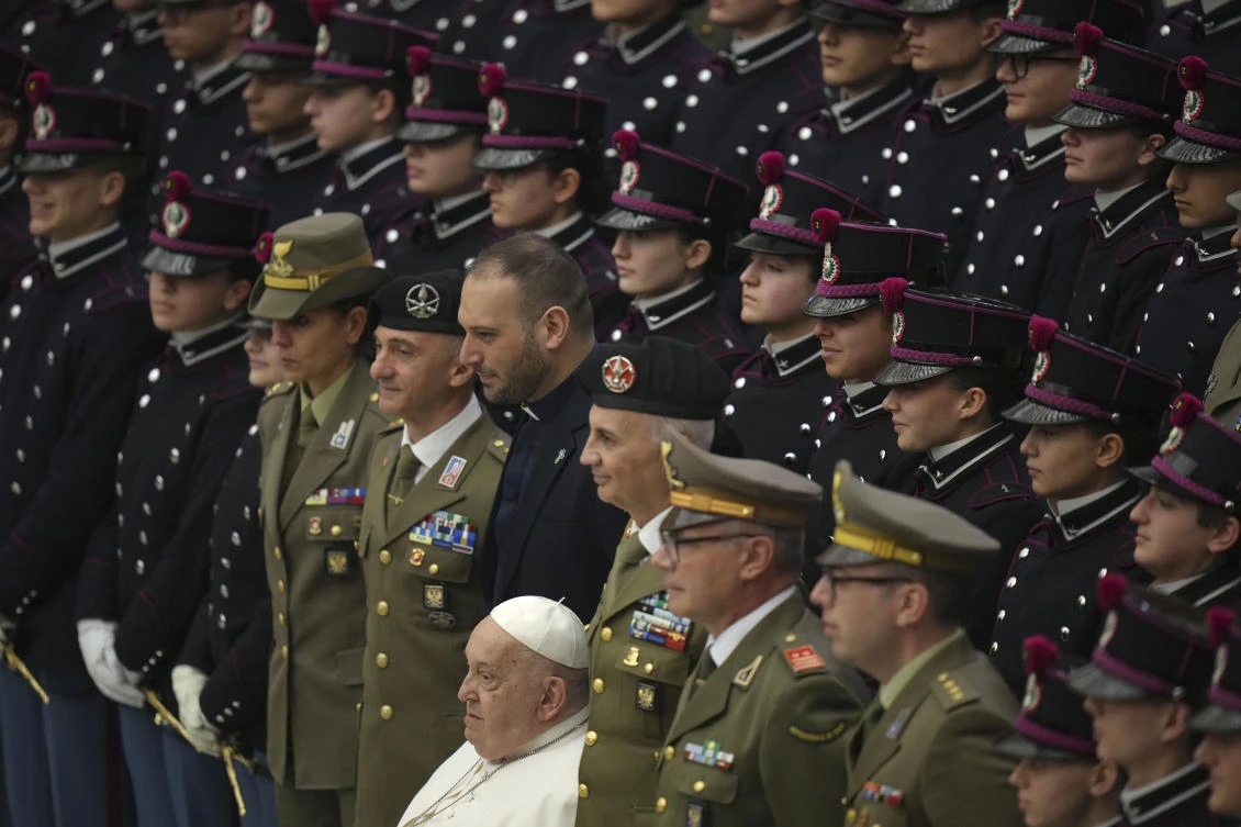 Pope Francis poses with armed forces members and cadets as he salutes the faithful at the end of his weekly general audience in the Paul VI Hall, at the Vatican, Wednesday, Feb. 12, 2025. (AP Photo)