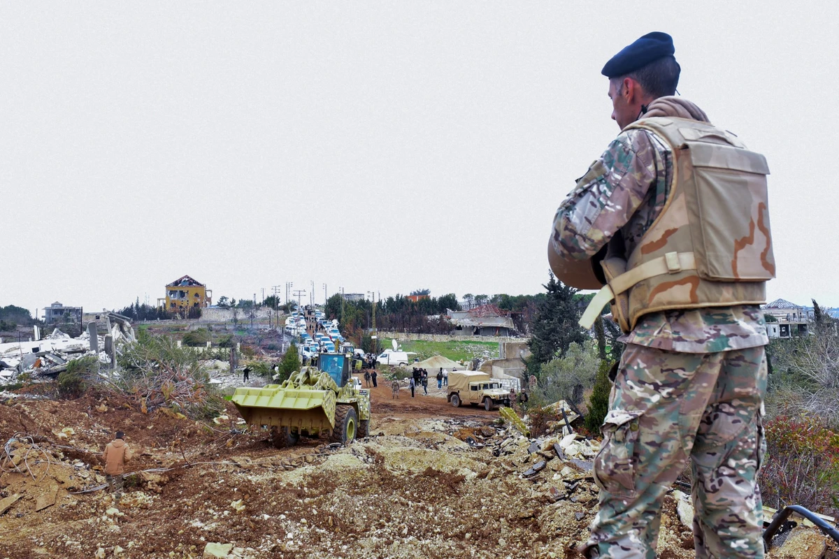 A Lebanese soldier stands guard after army deployment as a bulldozer opens a road for the residents of the southern village of Rubb Thlathin to return to their town on February 9, 2025.(AFP)