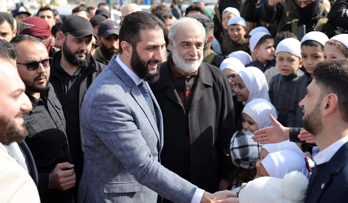 Syria’s President Ahmed Al-Sharaa visits people at a camp sheltering people displaced by the country’s civil war in the northwestern city of Idlib Saturday. (AFP)