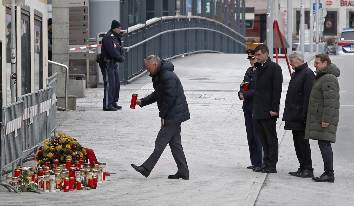 Austria's Interior Minister Gerhard Karner (L) places a candle on February 16, 2025 at the site where a man randomly attacked passers-by with a knife and stabbed to death a teenager and wounded five other people in Villach, Austria. (AFP)