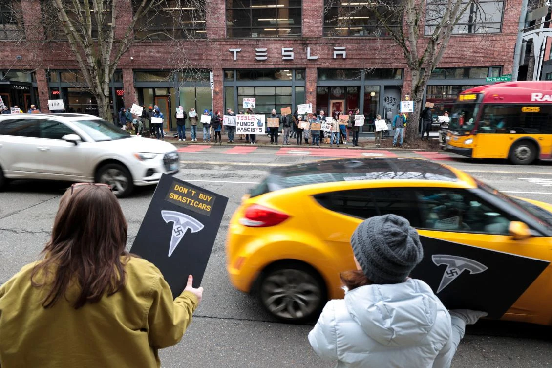 People participate in a "TeslaTakedown" protest against Elon Musk outside of a Tesla showroom in Seattle, Washington, on February 15, 2025. Musk leads the efforts under the newly created Department of Government Efficiency (DOGE), and was speaking at the White House with Trump, who has in recent weeks issued a flurry of orders aimed at slashing federal spending. (AFP)