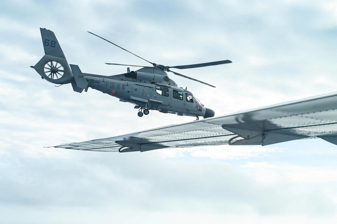 An aircraft identified as a Chinese navy helicopter, left, flies near a Philippine government fisheries aircraft during an aerial reconnaissance flight at Scarborough Shoal in the South China Sea on Feb. 18, 2025. (AFP)