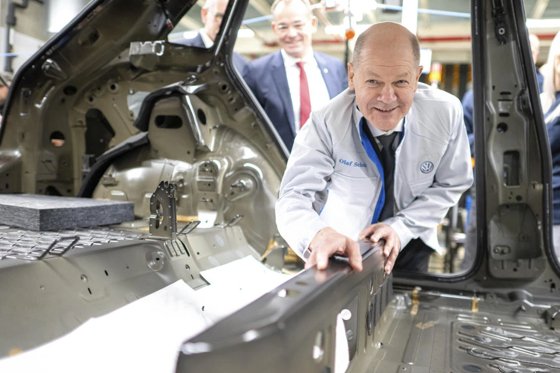 German Chancellor Olaf Scholz places an insulating mat in a car during a visit to a Volkswagen plant in Emden, Germany, Tuesday, Feb. 18, 2025. (AP Photo)