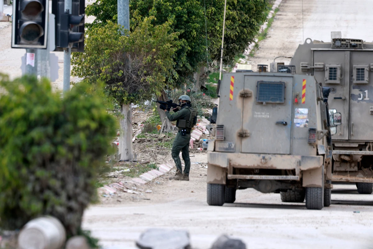 An Israeli soldier takes aim at the entrance of the occupied West Bank refugee camp of Tulkarem, during an ongoing military raid, Feb. 21, 2025. (AFP)