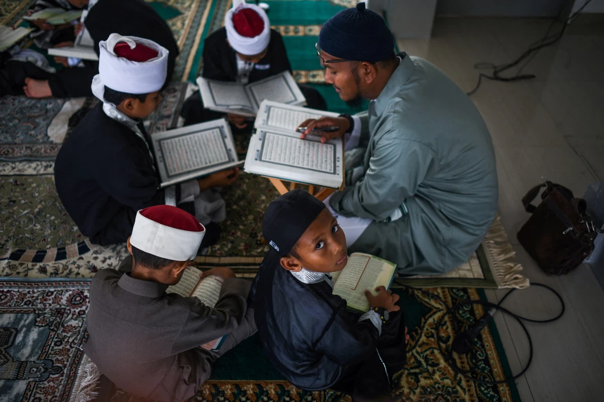This picture taken on May 22, 2019 shows Muslim students reading copies of the holy Koran to observe Nuzul Quran, when the beginnings of the Koran were revealed to the Prophet Mohammed, in a mosque in Bentong. Dressed in robes and chanting in Arabic, scores of Malaysian Muslim children read the Koran aloud in a mosque to mark a special date in the Islamic calendar. (AFP)