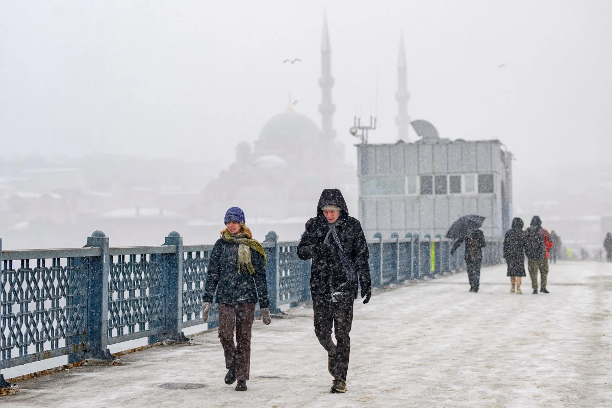 Pedestrians walk on the Galata Bridge as snow falls in Istanbul on February 21, 2025 (AFP)