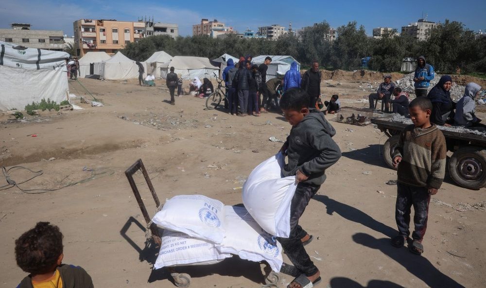 Palestinians boys load UNRWA food aid onto a cart, Nuseirat refugee camp, Gaza, Mar. 3, 2025. (AFP)