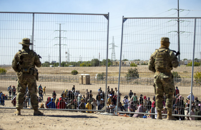 Migrants wait in line adjacent to the border fence under the watch of the Texas National Guard. (AP/File Photo)
