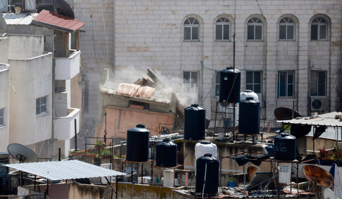 An Israeli military bulldozer demolishes a home at the Nur Shams camp for Palestinian refugees east of Tulkarem amid a weeks-long offensive in the occupied West Bank on March 1, 2025. (AFP)