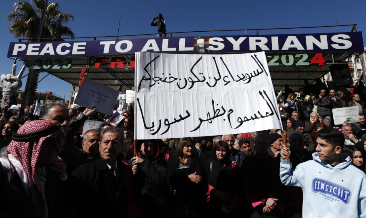 Syrian Druze hold up a placard in Arabic reads “Sweida will not be your poisoned dagger in Syria’s back.” as stage a demonstration against Israeli incursions into Syrian territory in the southern province of Sweida, Syria, Tuesday, Feb. 25, 2025. (AP)