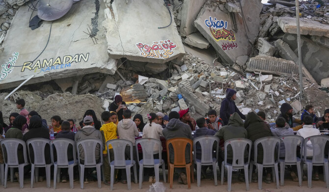 Palestinians sit at a large table surrounded by the rubble of destroyed homes and buildings as they gather for iftar, the fast-breaking meal, on the first day of Ramadan in Rafah in southern Gaza Strip on March 1, 2025 (AP)