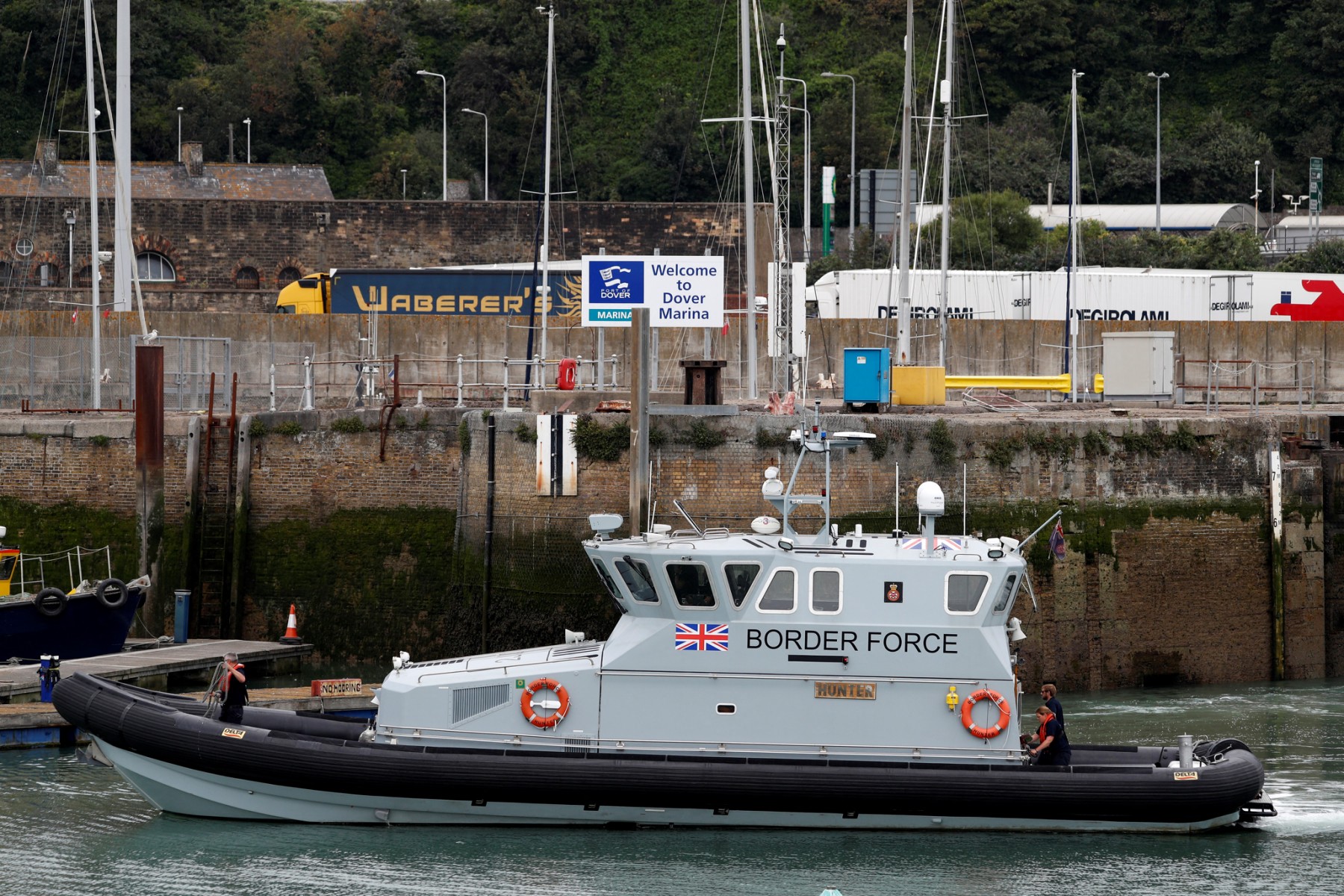 UK Border Force officials travel in a RIB with migrants picked up at sea whilst Crossing the English Channel, as they arrive at the Marina in Dover, southeast England on August 15, 2020. (AFP)