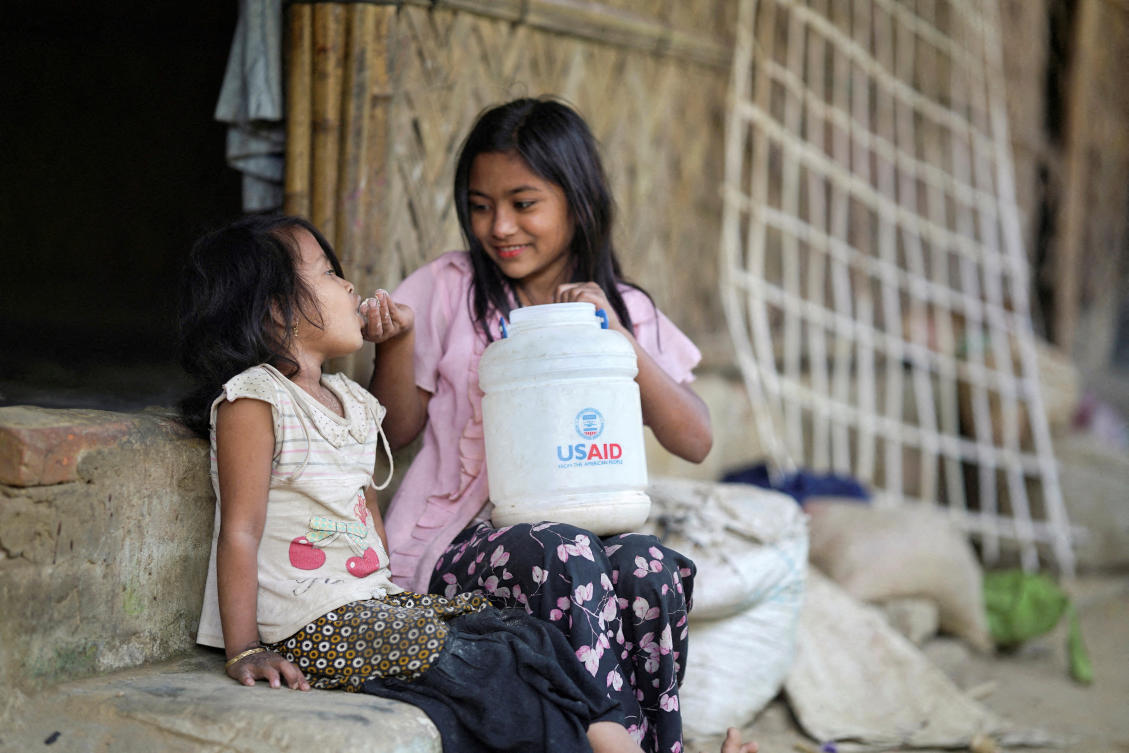 A Rohingya girl feeds a child from a jar with the USAID logo on it, at a refugee camp in Cox's Bazar, Bangladesh, February 11, 2025. (REUTERS)