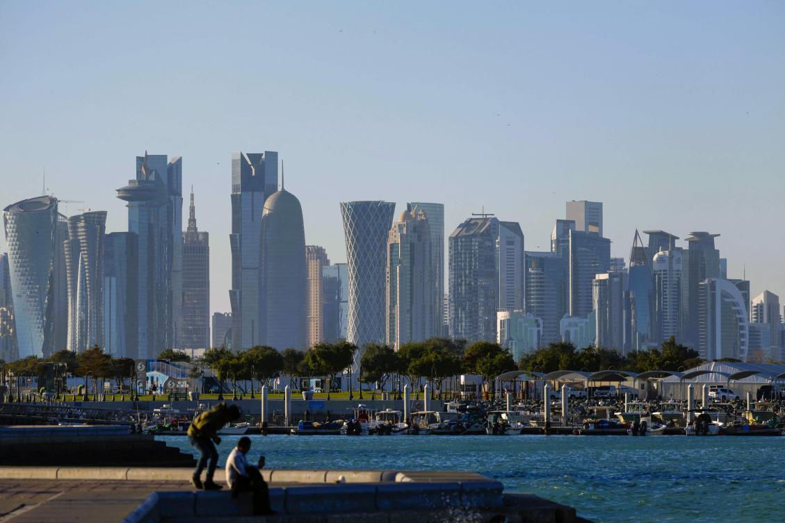 Men sit at the Doha Corniche backdropped by high buildings in Doha on March 3, 2025, during Ramadan. (AFP)