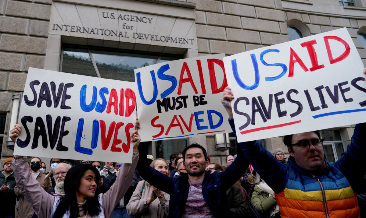 People hold placards, as the USAID building sits closed to employees after a memo was issued advising agency personnel to work remotely, in Washington, DC, US, February 3, 2025. (Reuters)