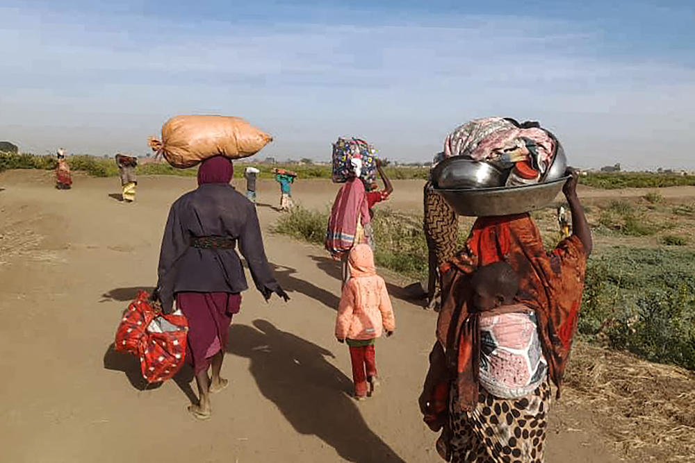 Above, displaced Sudanese women carry their belongings as the walk toward a camp near the town of Tawila in North Darfur on Feb. 11, 2025. (AFP)