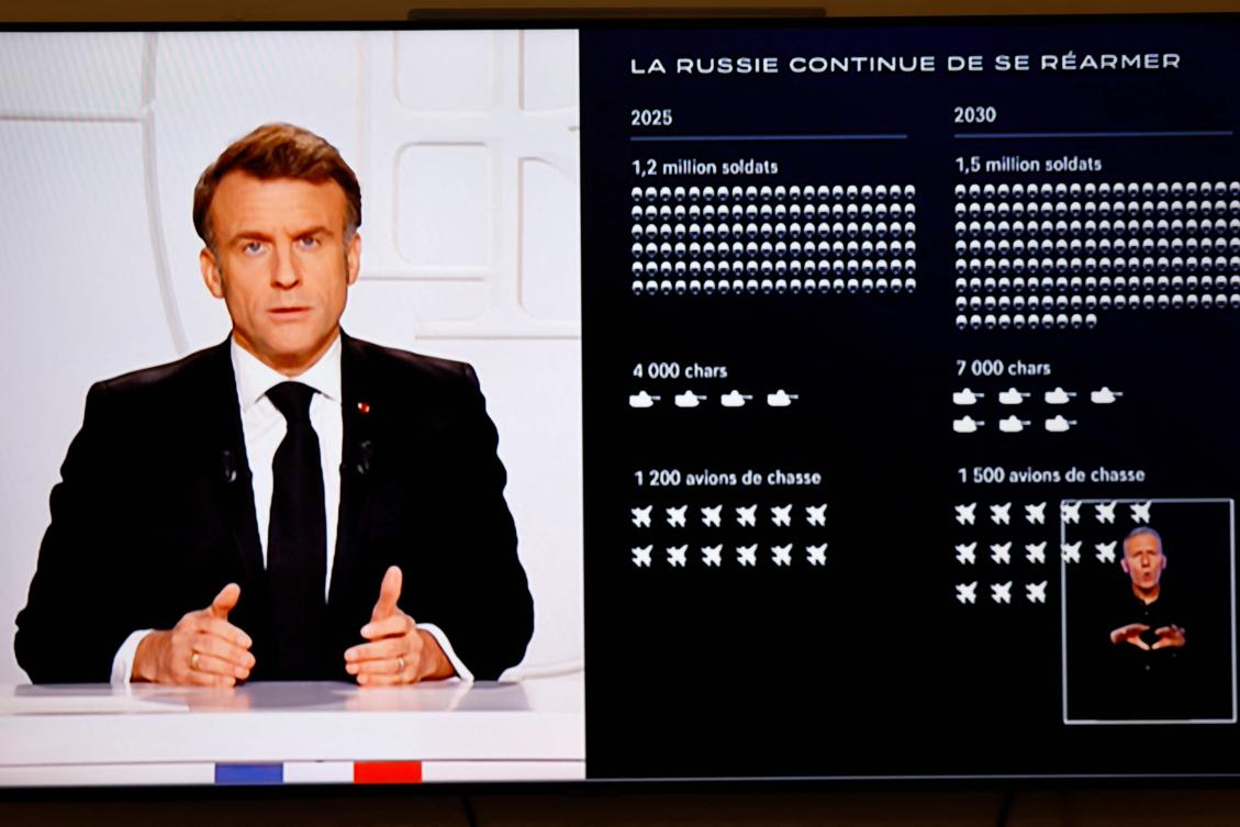 A television screen broadcasting France’s President Emmanuel Macron (L) addressing a live interview next to a graph showing the projected evolution of the Russian army, on French TV at the Elysee Presidential Palace in Paris. (AFP)