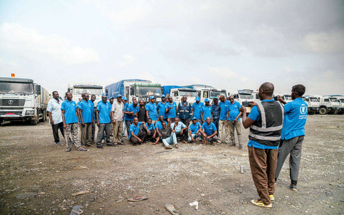 WFP workers pose for photos next to trucks carrying aid from Port Sudan to Sudan, November 12, 2024. (Reuters)
