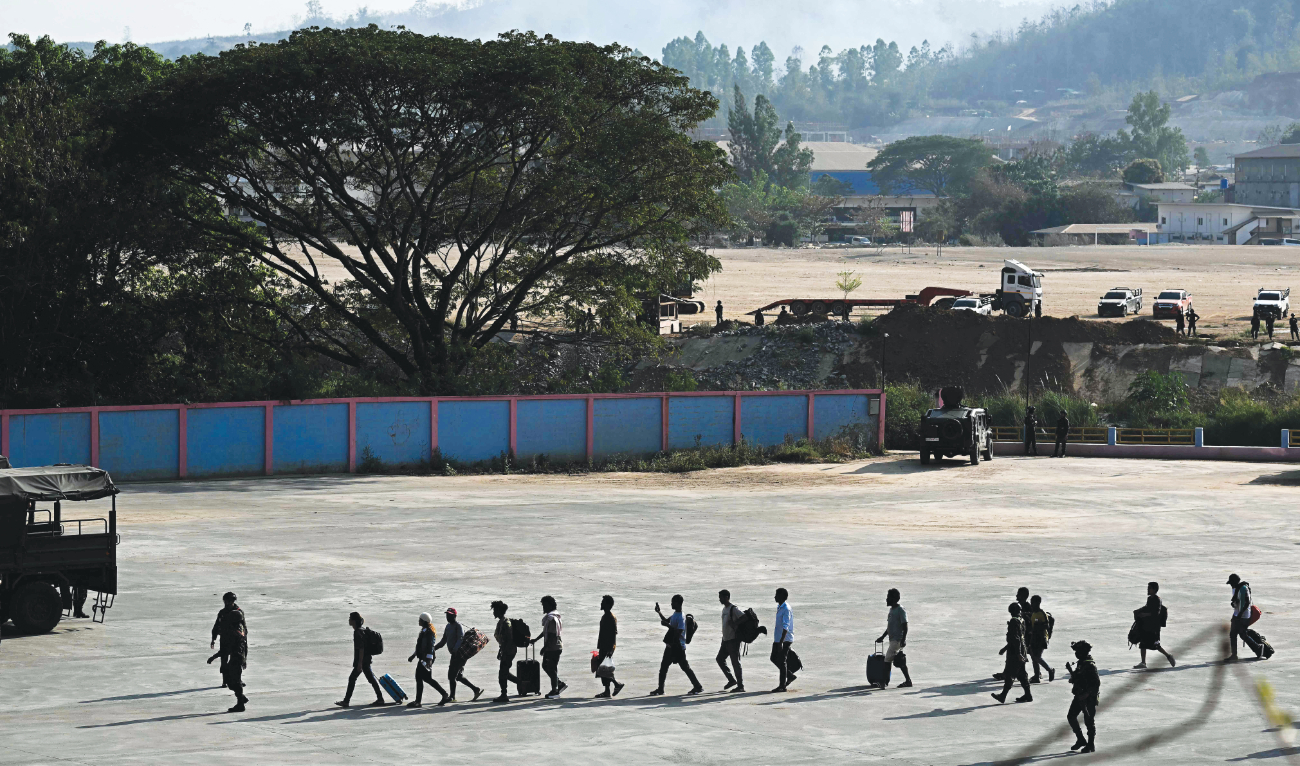 Alleged victims of scam centers in Kyauk Khet in Myanmar’s Kayin State walk in line as they are met by the Thai Army. (AFP)