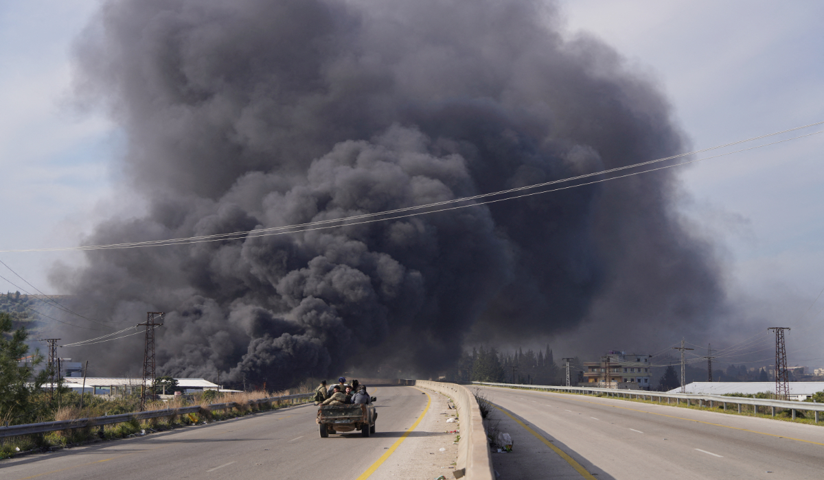 Smoke rises while members of the Syrian forces ride on a vehicle as they battle against a nascent insurgency by fighters from ousted leader Bashar al-Assad's Alawite sect, in Latakia, Syria March 7, 2025. (REUTERS)