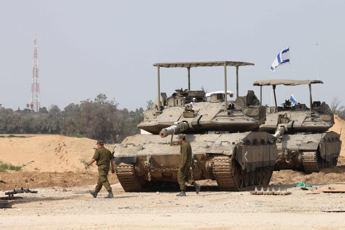 Israeli army soldiers walk past tanks at a position near Israel's southern border with the Gaza Strip on March 6, 2025. (AFP)