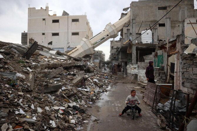 A Palestinian child rides a bicycle near a fallen minaret of a destroyed mosque during the Muslim holy fasting month of Ramadan, in the Nuseirat refugee camp in the central Gaza Strip on March 7, 2025. (AFP)