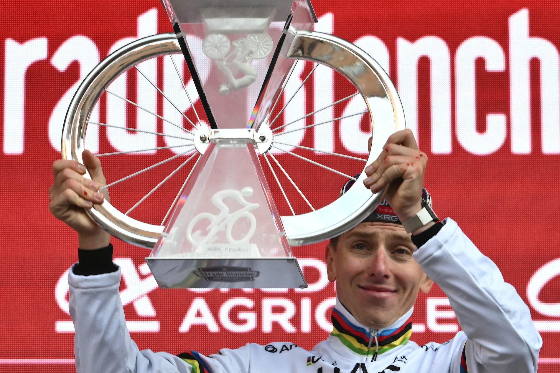 Team UAE's Slovenain rider Tadej Pogacar celebrates as he holds his trophy on the podium after winning the 19th one-day classic 'Strade Bianche' (White Roads) men's cycling race through uscany on March 8, 2025. (AFP)