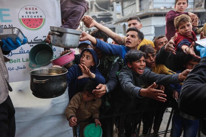 Displaced Palestinian children push into a queue to get a portion of cooked food from a charity kitchen in Beit Lahia in northern Gaza Strip, ahead of iftar during Ramadan on March 9, 2025. (AFP)