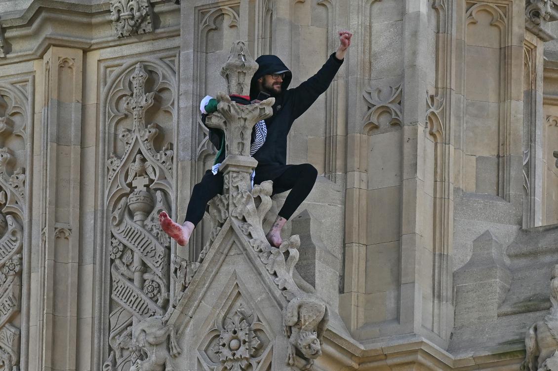 A protester holding a Palestinian flag gestures from the side of the Elizabeth Tower at the Palace of Westminster, home to the Houses of Parliament, in central London, on March 8, 2025. (AFP)