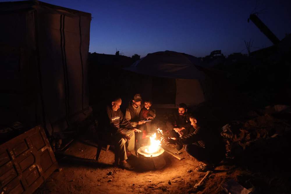 Palestinians gather around a fire to keep warm in Jabalia in the northern Gaza Strip on March 10, 2025. (AFP)